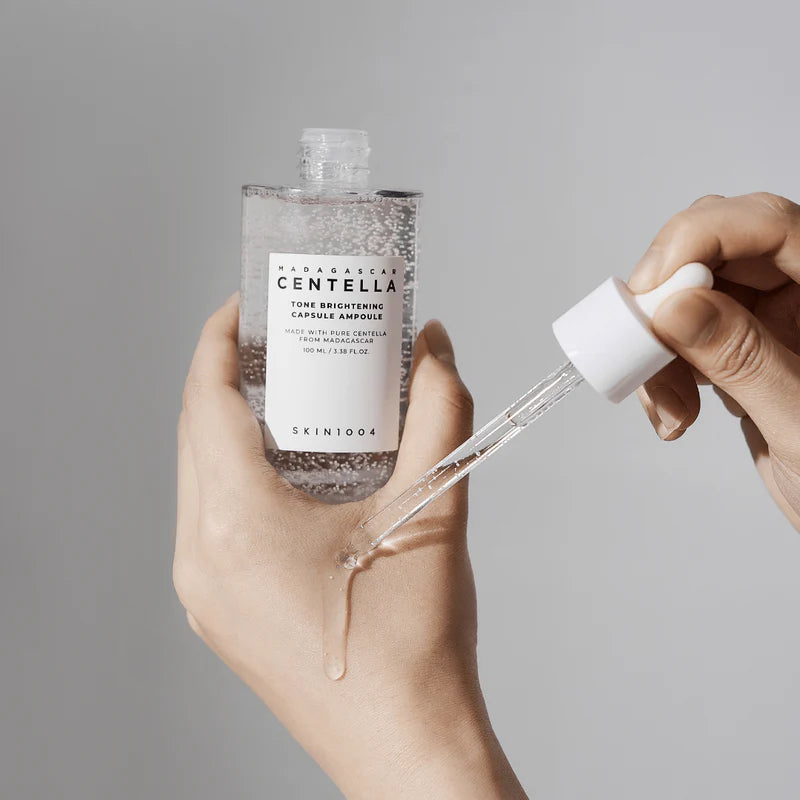 Skincare product with dropper bottle held by a hand against a neutral background